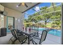 Relaxing screened patio featuring a table and chairs overlooking sparkling swimming pool at 18631 Le Dauphine Pl, Lutz, FL 33558