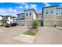 Home exterior with individual garages, neutral stucco, front yard landscaping, and paver driveway with parked car at 29901 Southwell Ln, Wesley Chapel, FL 33543