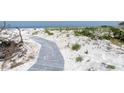 Private beach access with a winding boardwalk through white sands and native greenery at 3200 Gulf Blvd # 202, St Pete Beach, FL 33706