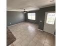 Well-lit living room with tile flooring, ceiling fan, and a bright white front door at 37913 Wicklow Ave, Zephyrhills, FL 33541