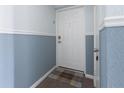 A white front door with a neutral-colored doormat in a condo hallway with blue and white walls at 5012 Starfish Se Dr # B, St Petersburg, FL 33705