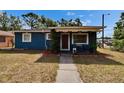 Charming blue home featuring a red front door and well-manicured lawn at 6409 N 23Rd St, Tampa, FL 33610