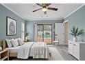 Bright main bedroom with light blue walls, light wood flooring, a ceiling fan, and a sliding glass door to the backyard pool at 9107 Spring Hill Dr, Spring Hill, FL 34608
