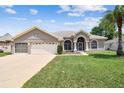 Charming single-story home featuring a manicured lawn, arched windows, and a spacious two-car garage at 9219 Irondale Ln, Hudson, FL 34667