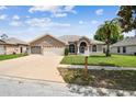 Well-maintained single-story home featuring a manicured lawn, arched windows, and a spacious two-car garage at 9219 Irondale Ln, Hudson, FL 34667