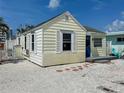Quaint yellow cottage featuring white trim, a blue front door, and a shell driveway exudes coastal charm at 13326 1St E St, Madeira Beach, FL 33708