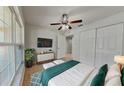 Cozy bedroom with a ceiling fan, white closet doors, and a large window for ample natural light at 1850 Fuller Dr, Clearwater, FL 33755
