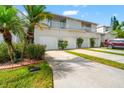 Inviting townhome exterior featuring garages, manicured landscaping, and vibrant palm trees at 1936 Heron Cove Dr # 104, Lutz, FL 33549