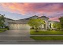 Charming single-story home features a 3-car garage and a beautifully landscaped front yard at sunset at 21642 Emory Oak Pl, Land O Lakes, FL 34637
