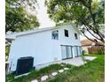 The home's back exterior has a white facade with sliding glass doors and a lush green yard at 2233 Springwood W Cir, Clearwater, FL 33763