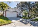 Inviting single-story home boasting a well-kept lawn, two-car garage and mature trees at 2233 Springwood W Cir, Clearwater, FL 33763