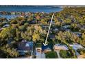 An aerial view shows a home surrounded by lush trees with a waterfront view and its position in the neighborhood at 3165 Renatta Dr, Belleair Bluffs, FL 33770
