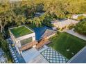 An aerial view showcases a modern home's rooftop deck, geometric driveway, and proximity to lush surroundings at 3165 Renatta Dr, Belleair Bluffs, FL 33770