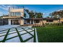 A modern home featuring a two-story design, sleek lines, a large deck, and a unique geometric driveway pattern at 3165 Renatta Dr, Belleair Bluffs, FL 33770
