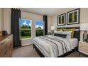 Serene bedroom with a view of trees, featuring a patterned bedspread, dark curtains, and coordinated decor at 37017 Sagemoor Dr, Zephyrhills, FL 33541