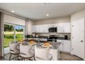 Bright, open kitchen with island seating, white cabinetry, modern appliances, and a sliding door view of the backyard at 37122 Sagemoor Dr, Zephyrhills, FL 33541