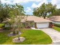 Well-maintained home with a tile roof, lush green lawn, and a two-car garage, offering great curb appeal at 5812 Garden Lakes Majestic, Bradenton, FL 34203