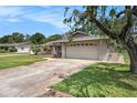 Single-story home with a two-car garage, green lawn, and mature trees at 5905 Berkford Dr, Holiday, FL 34690