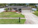 An attractive single-story home features a well-manicured lawn and a spacious driveway at 5905 Berkford Dr, Holiday, FL 34690