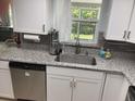 The Kitchen features stainless steel appliances, a granite countertop, tiled backsplash, and white cabinets at 7524 Oakshire Dr, Port Richey, FL 34668