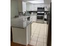 Bright kitchen featuring white cabinets, stainless steel appliances, granite countertops, and tile flooring at 7524 Oakshire Dr, Port Richey, FL 34668