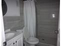 Bathroom showcasing neutral tile walls, a toilet, and a walk-in shower with curtain at 8503 N Willow Ave, Tampa, FL 33604