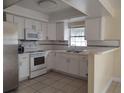 Well-lit kitchen with white cabinetry, stainless steel appliances, and a breakfast bar at 8503 N Willow Ave, Tampa, FL 33604