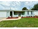 Charming single-story home featuring a manicured lawn and fresh landscaping around the entrance at 9005 Rainbow Ln, Port Richey, FL 34668