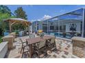 Outdoor dining area featuring covered grill, table and chairs, and a screened in porch at 9208 Brindlewood Dr, Odessa, FL 33556