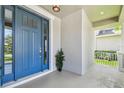 Inviting front porch with a blue door, a small potted plant, and a view of the landscaped yard at 9317 Bella Vita Cir, Land O Lakes, FL 34637