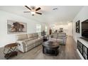 Bright living room features neutral decor, wood-look tile flooring and an open layout to the kitchen at 10098 Banyan Breeze Blvd, Land O Lakes, FL 34638
