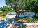 Charming single-story home with a mature tree in the front yard and a detached garage at 1221 E Hamilton Ave, Tampa, FL 33604