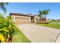 A single-story home has neutral siding, a two-car garage and small palm trees in the front yard at 13201 Wellington Hills Dr, Riverview, FL 33579