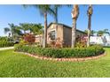 A beautiful landscaping bed features tropical bushes and small palm trees in this single-Gathering neighborhood at 13201 Wellington Hills Dr, Riverview, FL 33579