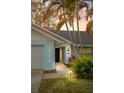 Charming home exterior featuring a blue accent wall, well-lit entrance, and lush landscaping at 1394 Stonehenge Way, Palm Harbor, FL 34683
