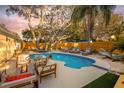A luxurious backyard featuring a sparkling pool, comfortable lounge chairs, and a cozy fire pit area at 1394 Stonehenge Way, Palm Harbor, FL 34683