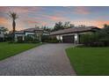 Exterior view of a house with well-manicured lawn, mature landscaping, and a brick-paved driveway at 14910 Tom Fazio Ct, Tampa, FL 33626