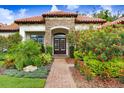 Elegant home exterior with a stone archway entrance, double doors, and vibrant flowering bushes at 14910 Tom Fazio Ct, Tampa, FL 33626