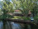 Spacious backyard with a waterfront view, mature trees, and a covered patio area at 18712 Lakeshore Dr, Lutz, FL 33549