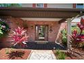 Elegant entryway with brick accents, a covered porch, and a decorative glass front door at 18712 Lakeshore Dr, Lutz, FL 33549
