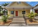 Inviting yellow home featuring a classic front porch and well-manicured landscaping at 2402 Harper St, Tampa, FL 33605