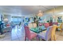 Bright dining room featuring a glass table, colorful chairs, chandelier and views of the ocean at 2504 Gulf Blvd # 201, Indian Rocks Beach, FL 33785