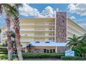 Exterior view of the Dolphin Reef condo building with stone accents, manicured landscaping, and palm trees at 2504 Gulf Blvd # 201, Indian Rocks Beach, FL 33785