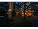 Home illuminated at dusk, surrounded by mature trees and lush landscaping at 420 Hanby St, Crystal Beach, FL 34681