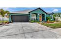 Beautiful teal home featuring manicured landscaping, red front door, and a two-car garage at 5103 Rushbrook Rd, Land O Lakes, FL 34638