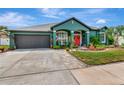 Beautiful teal home featuring manicured landscaping, a red front door, and a two-car garage at 5103 Rushbrook Rd, Land O Lakes, FL 34638