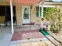 Inviting home entrance with a covered walkway and colorful brick path leading to the front door and a small putting green at 7425 W Maryland W Ave, Hudson, FL 34667