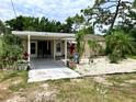 Welcoming home featuring a carport, tropical landscaping, and a well-manicured lawn at 7425 W Maryland W Ave, Hudson, FL 34667