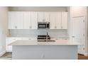 Modern kitchen with white cabinets, stainless steel appliances, and a center island with a sink at 10018 Surrey Rose Dr, San Antonio, FL 33576