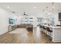 Open-concept living room featuring wood floors, ceiling fan, large windows, and breakfast bar seating at 10625 Cardera Dr, Riverview, FL 33578